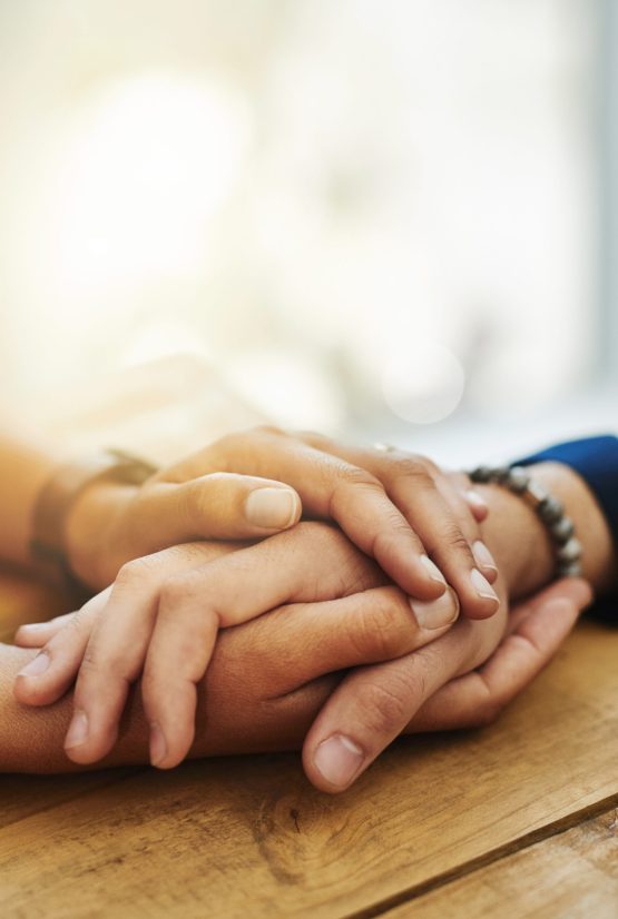Closeup shot of two unrecognizable people holding hands in comfort.